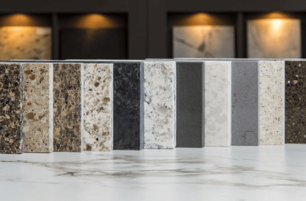 A row of diverse rectangular countertop stone samples displayed on a white marble surface.